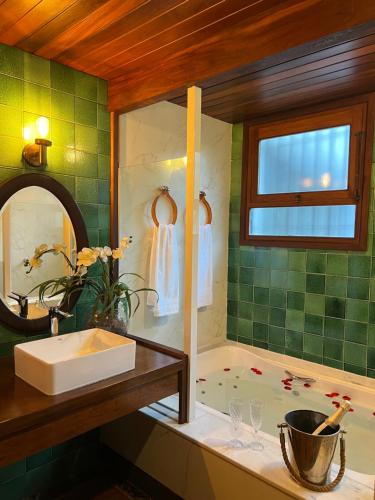 a bathroom with a tub and a sink and a mirror at Casa Holanda - Suite Austria c jacuzzi in Teresópolis