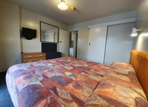 a hotel room with a large bed and a television at Distinction Heritage Gateway Hotel in Omarama