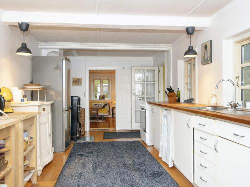 a large kitchen with white cabinets and a sink at Lakeside Holiday Home with Forest in Vilholt
