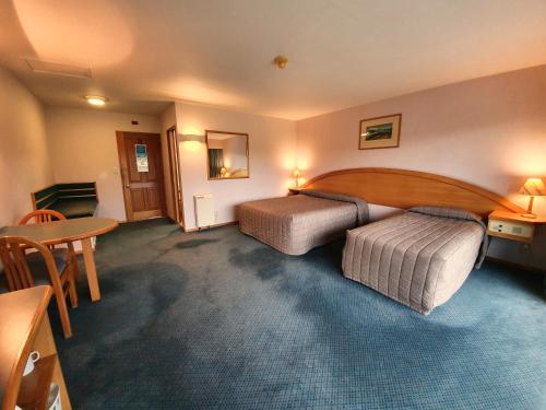 a hotel room with two beds and a table at Distinction Heritage Gateway Hotel in Omarama