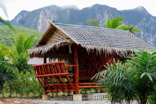 małą chatę z dachem krytym strzechą i krzesłami w obiekcie Khaosok River Stone Resort & Camp w mieście Ban Thung Lang Tham