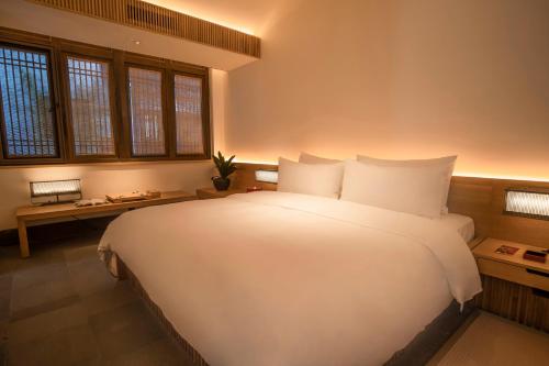 a large white bed in a room with windows at 南京夫子庙夜泊秦淮水街酒店 in Nanjing