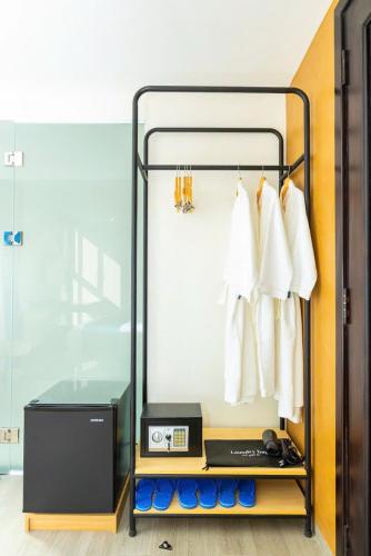 a closet with a rack with white shirts and a clock at Bacada in Quy Nhon