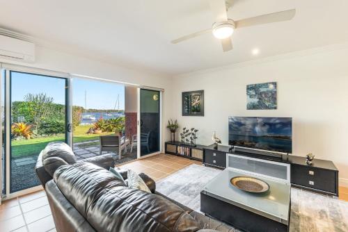 a living room with a leather couch and a tv at Riverview Apartment 1 Block 1 in Iluka