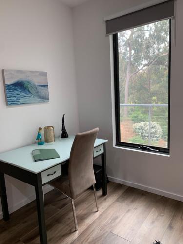 a desk and a chair in a room with a window at Gillys Guesthouse in Metung
