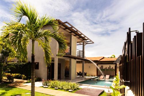 a house with a palm tree and a swimming pool at Pousada Pedra da Pipa in Pipa