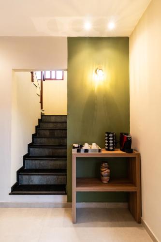 a staircase with a green wall and a table and stairs at Pousada Pedra da Pipa in Pipa