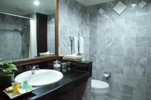a bathroom with a sink and a toilet and a mirror at The Jayakarta Bali Beach Resort in Legian
