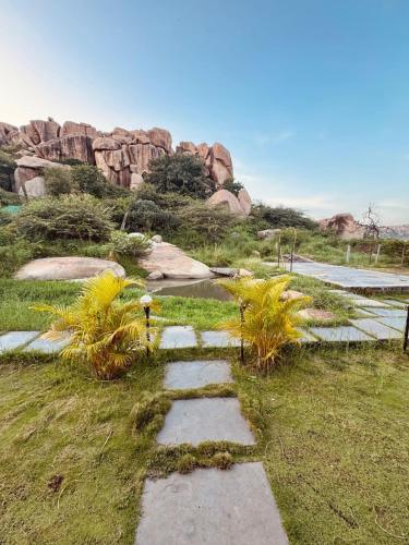a stepping stone path in a field with plants at Murali Guesthouse Hampi in Hampi