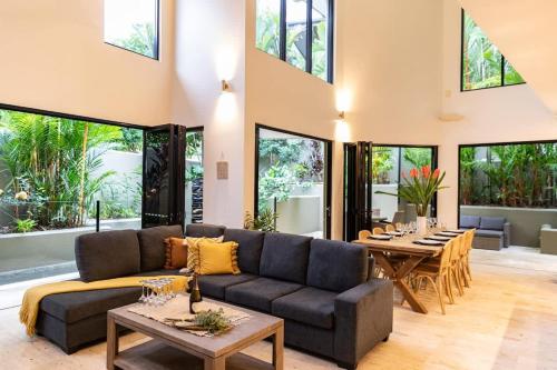 a living room with a couch and tables and windows at Villa Amalfi - Port Douglas in Port Douglas