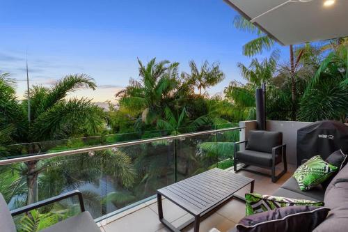 a balcony with a couch and a chair and palm trees at Villa One on Murphy in Port Douglas