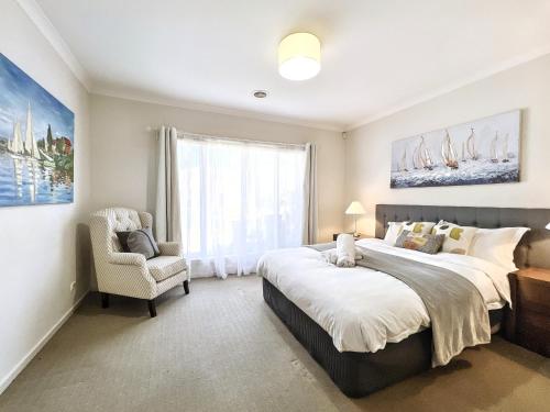 Un dormitorio con dos camas y una silla y una ventana. en Modern Golfside Retreat, en Carrum Downs