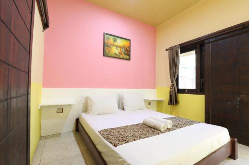 Brown Sugar Homestay في غيلي تراوانغان: غرفة نوم بسرير ابيض بجدار وردي