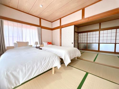 a bedroom with two beds in a room with windows at 海しずくLittle in Kami Amakusa