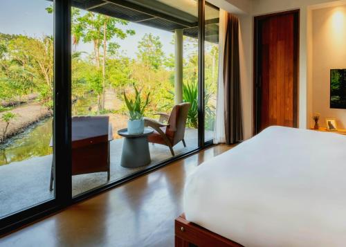 a bedroom with a bed and a view of a garden at Coconut Lane Bangkok in Bangkok