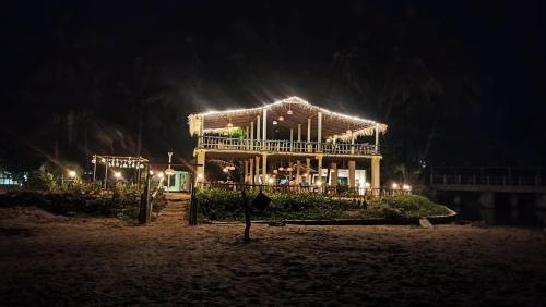 a house with lights on the beach at night at Coconut tree cafe Gokarna in Gokarna