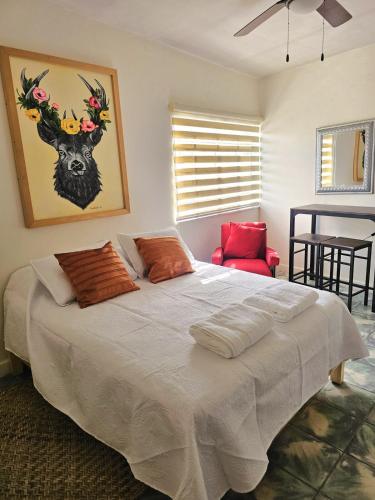 a bedroom with a large white bed with a red chair at Casa Centurias céntrico con mini Split in Aguascalientes
