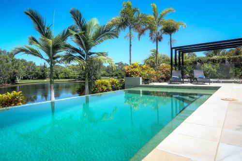 a swimming pool in a villa with palm trees at Tranquility by the Lake - Luxury Home Port Douglas in Port Douglas