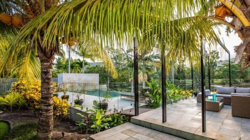 a patio with a palm tree and a swimming pool at Tranquility by the Lake - Luxury Home Port Douglas in Port Douglas