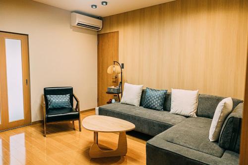 ein Wohnzimmer mit einer Couch und einem Tisch und einem Stuhl in der Unterkunft T304Japanese Garden Villa near Historic Town Max of 8 people in Takayama