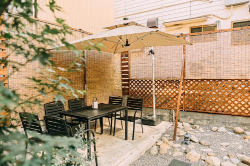 einen schwarzen Tisch und Stühle mit einem Sonnenschirm in der Unterkunft T304Japanese Garden Villa near Historic Town Max of 8 people in Takayama