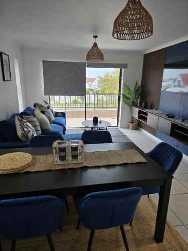 Una sala de estar con una mesa y sillas azules. en Coastal Cove Langebaan, en Langebaan