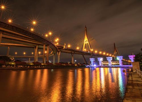 a bridge with lights on the water at night at Coconut Lane Bangkok in Bangkok