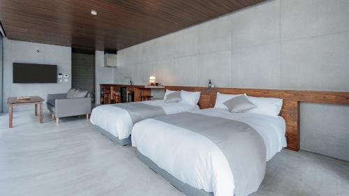 a hotel room with two beds and a television at Tanegashima Araki Bekkan in Nishinoomote
