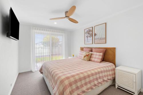 Un dormitorio con una cama y un ventilador de techo. en Amos Court luxury, en Ocean Grove