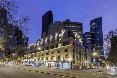 a building with street lights in a city at night at Great Southern Hotel Melbourne in Melbourne