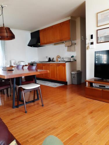 a living room with a table and a kitchen at ゲストハウス苫小牧 202号室 in Tomakomai