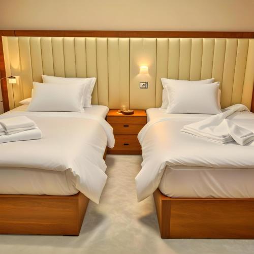 a bedroom with two beds and a night stand at Pyramids Grand View Hotel in Cairo
