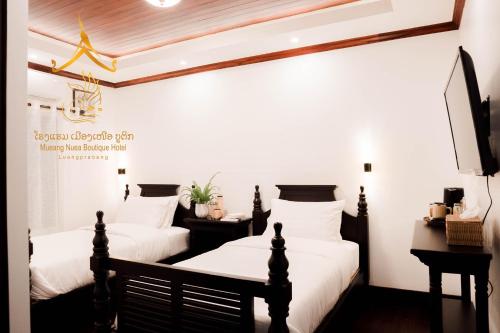 two beds in a room with white walls at Mueang Nuea Boutique Hotel in Luang Prabang