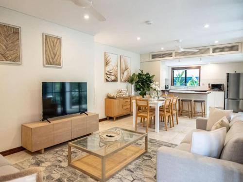 a living room with a couch and a tv and a table at 25 Solander Boulevard - Seashells, Port Douglas in Port Douglas