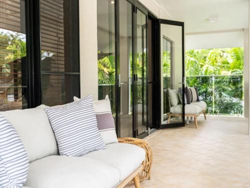 a living room with a white couch and glass doors at 25 Solander Boulevard - Seashells, Port Douglas in Port Douglas