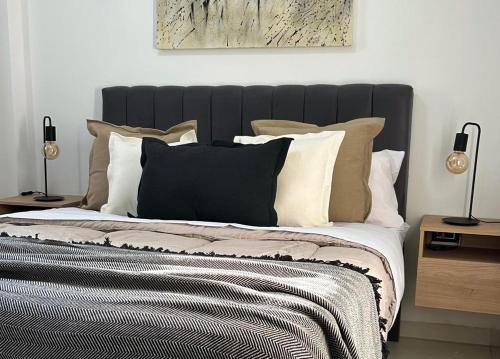 a bed with a black headboard and pillows on it at Moderno departamento en el centro de la ciudad in San Fernando del Valle de Catamarca