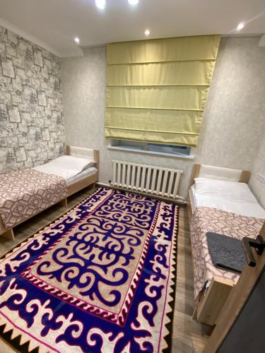 a room with two beds and a rug on the floor at Apart Le Mont in Karakol