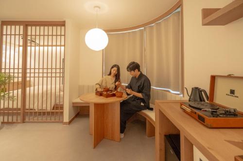 a man and woman sitting at a table in a room at 메종 드 온유 호텔 전주 한옥마을점 in Jeonju
