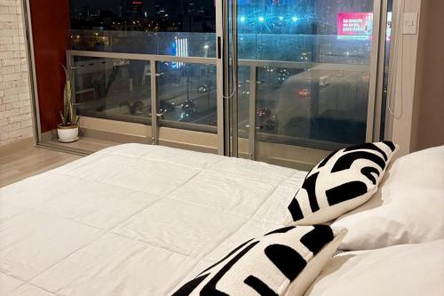 1 cama con almohadas blancas y negras frente a una ventana en Acogedor Loft con ubicación céntrica en Lima, en San Antonio