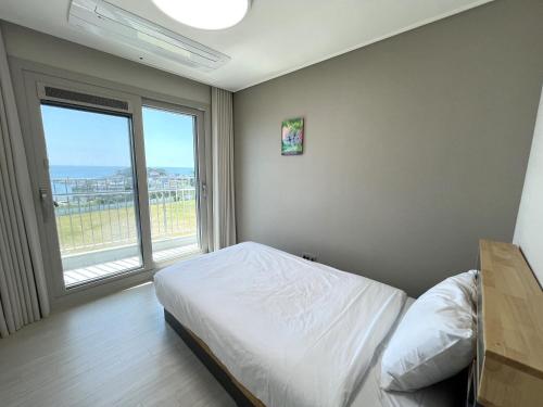 a bedroom with a bed and a large window at SoYou osiria residence in Busan
