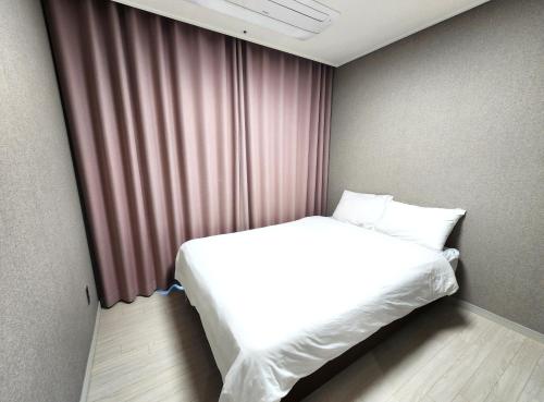 a white bed in a room with a window at SoYou osiria residence in Busan