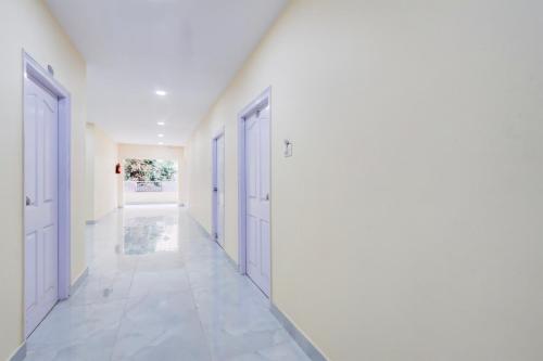 an empty hallway with white walls and white doors at Hotel O Ss ome inn ultra luxury rooms in Ameerpet