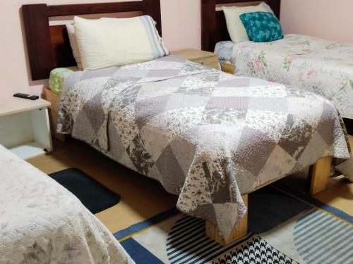 a room with three beds and a table with a quilt at Hostal Antonio Varas in Concepción