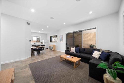 a living room with a black couch and a table at Casa al mare - Bribie Island 5BD Retreat in Woorim