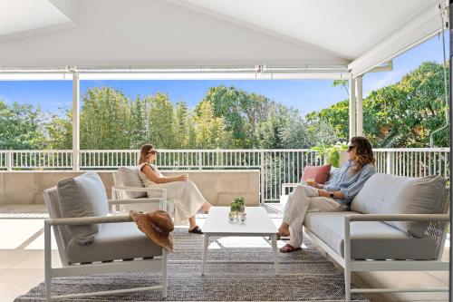 two women sitting on the porch of a house at Casa al mare - Bribie Island 5BD Retreat in Woorim