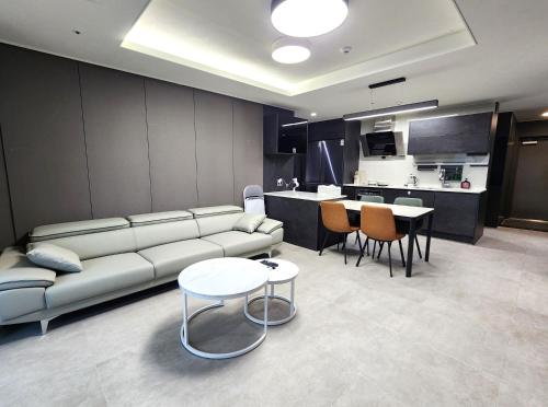 a living room with a couch and tables and a kitchen at SoYou osiria residence in Busan