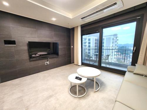 a room with a couch and a table and a tv at SoYou osiria residence in Busan