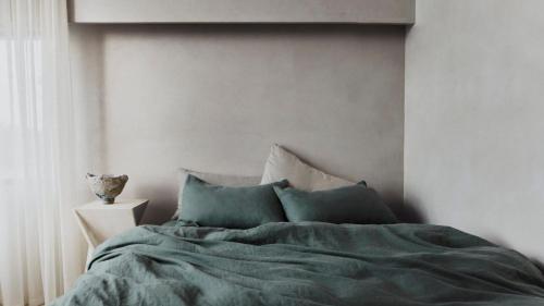 a bed with green sheets and pillows in a bedroom at Escape to Summer, Bilgola Plateau IH Luxe in Bilgola