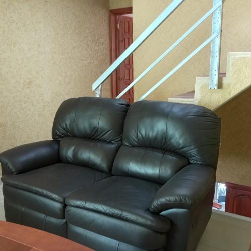 a black leather couch sitting next to a staircase at Casa Cielo Lindavista in Tulancingo
