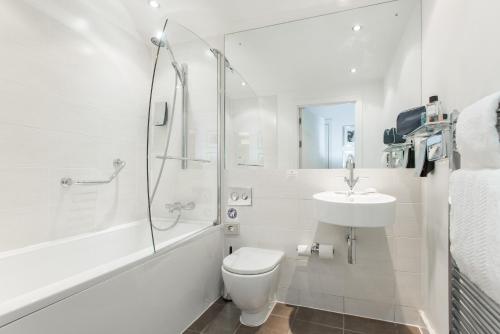 a bathroom with a toilet and a sink and a shower at PREMIER SUITES Manchester in Manchester